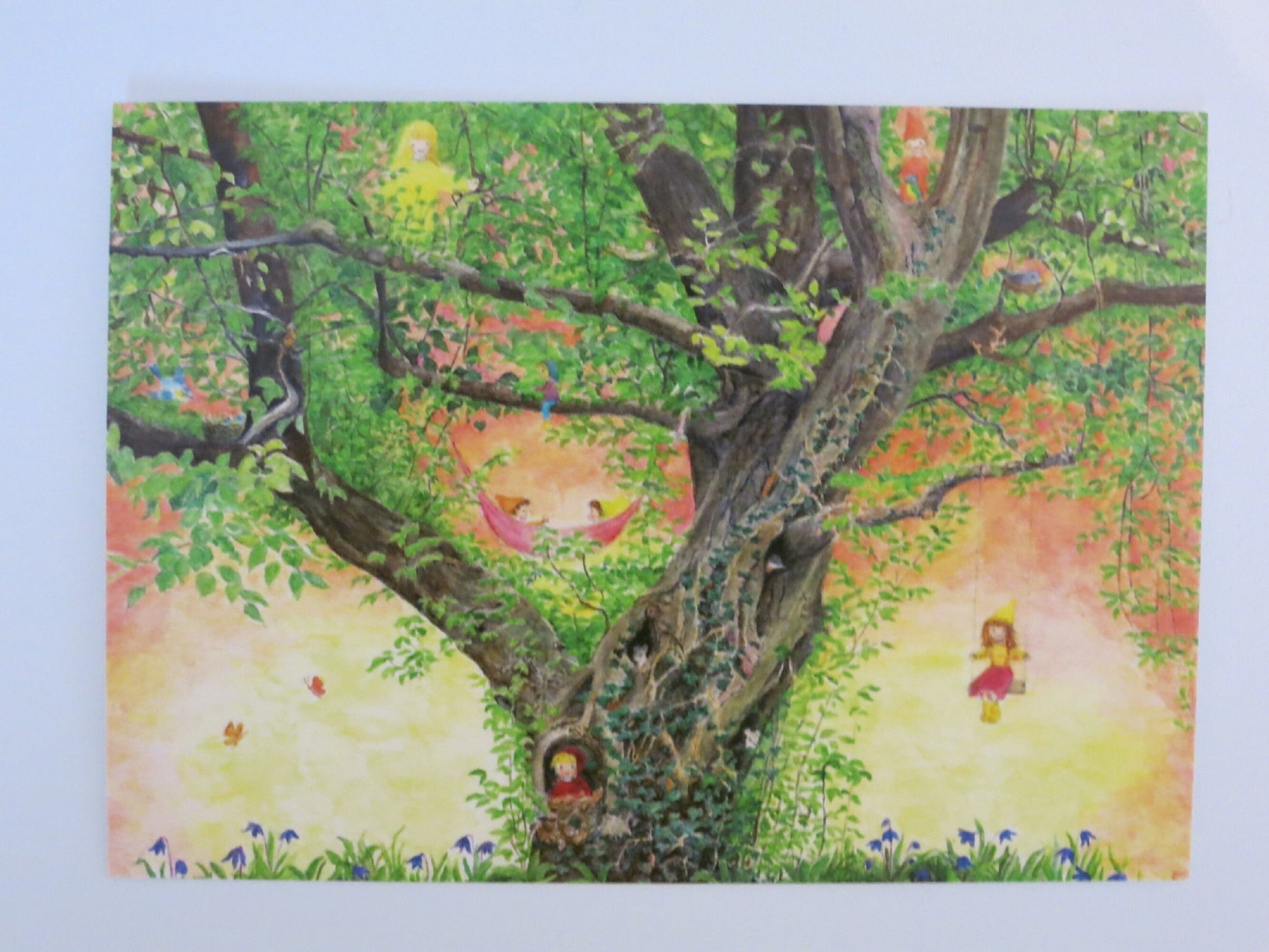 Postkarte Hagebuche: Baum mit Wichteln in Hängematte, Kind auf Schaukel und Zwerg im Geäst, Aquarell von Elisabeth Heuberger