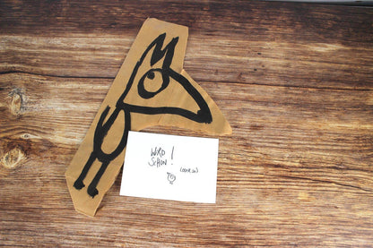 Postkarte Wird schon! vor einem gezeichneten Tier auf Packpapier auf Holz