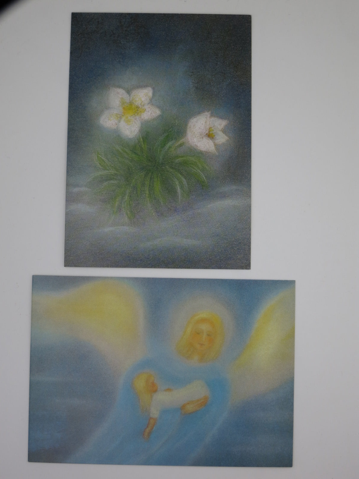 Zwei Karten aus dem Postkartenset Winter: Christrosen und Engel in blauem Licht
