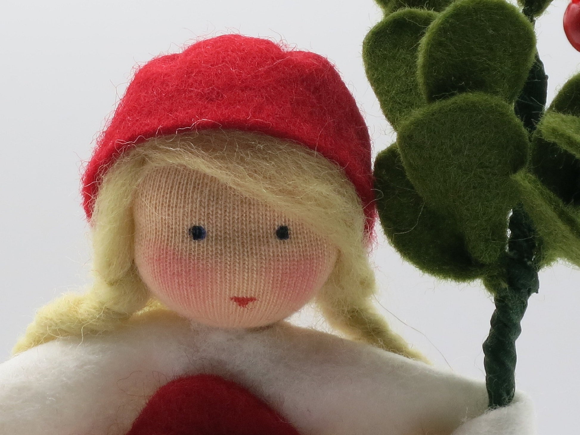 Nahaufnahme des gestickten Gesichts am Preiselbeere-Blumenkind, Waldorf-Puppenfigur