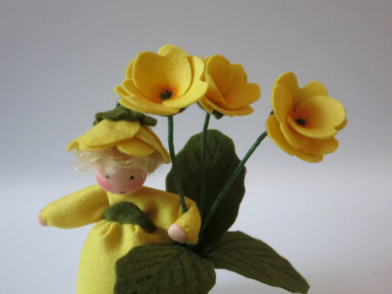 Gesicht des Primelchen Blumenkindes, Nahaufnahme Wollfilz Waldorfpuppe mit gelber Blütenhaube