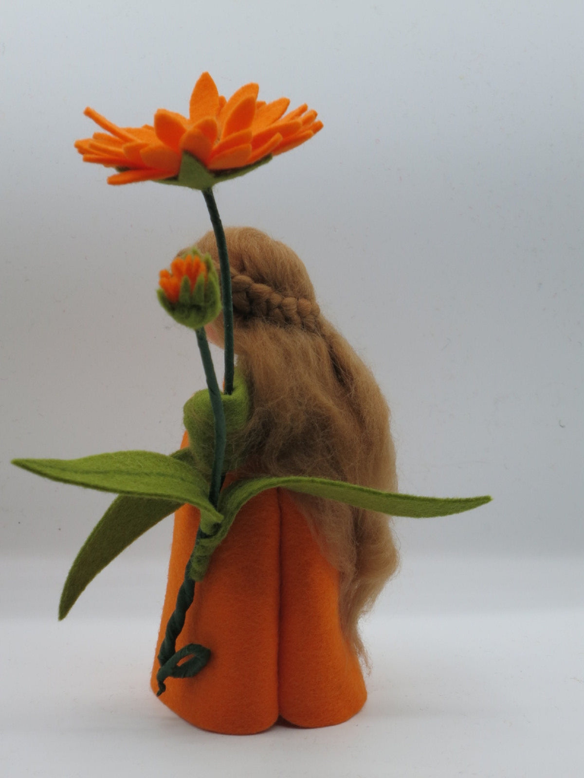 Seitenansicht der Ringelblumen-Figur mit orangem Kleid und grünen Ärmeln.