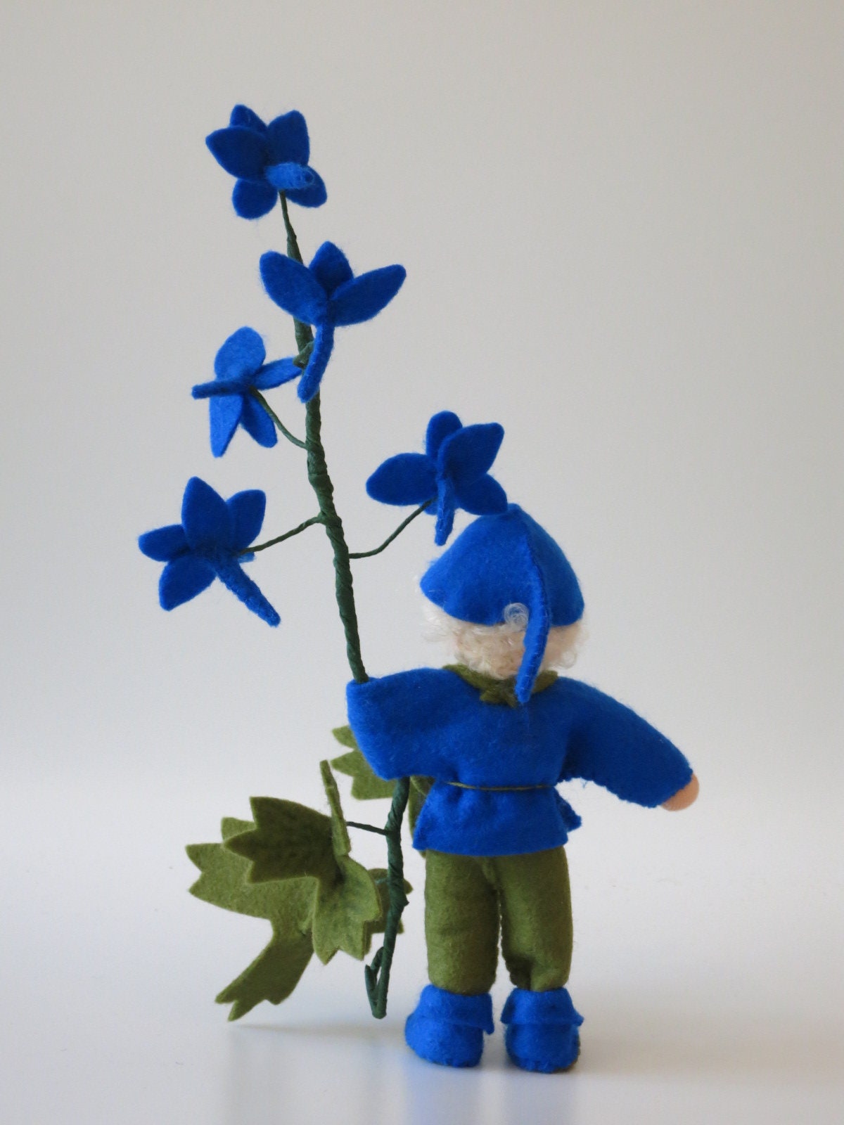 Rückansicht des Rittersporn-Blumenkindes mit blauer Filzmütze, Waldorf-Jahreszeitentisch