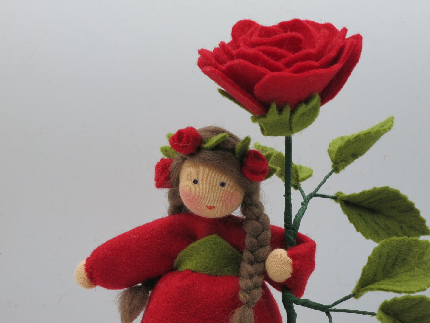 Nahaufnahme Gesicht Rose-Blumenkind mit Rosenkranz aus Wollfilz, Waldorf-Jahreszeitentisch