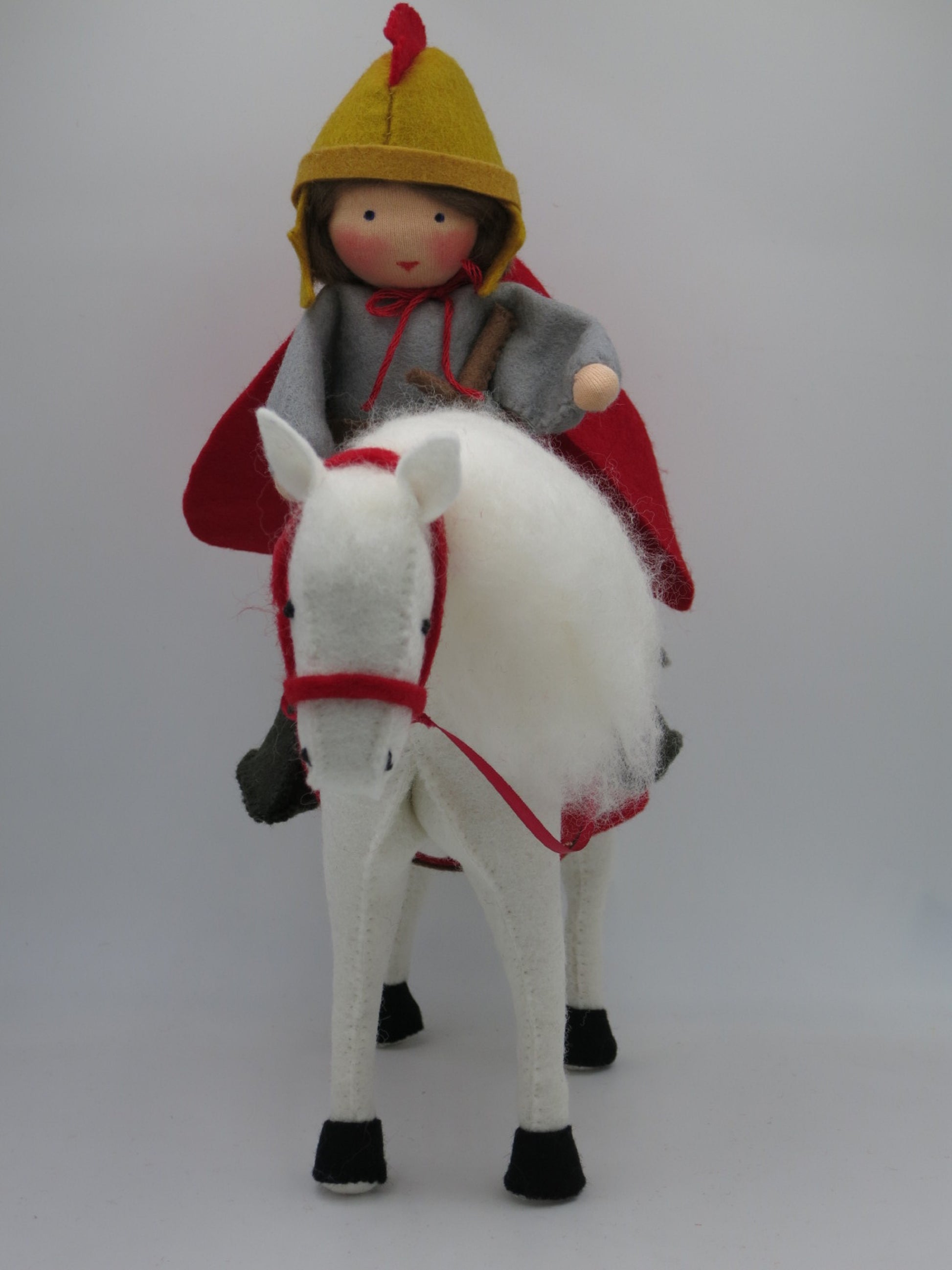 Frontalansicht von Sankt Martin Art. HE66 zu Pferd mit goldenem Helm und rotem Umhang, Waldorf-Blumenkind für den Jahreszeitentisch.