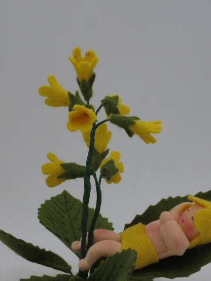 Schlüsselblumen Baby Gesamtansicht mit Filzschlüssel, schlafendem Gesicht und gelber Blütenrispe für den Waldorf Jahreszeitentisch