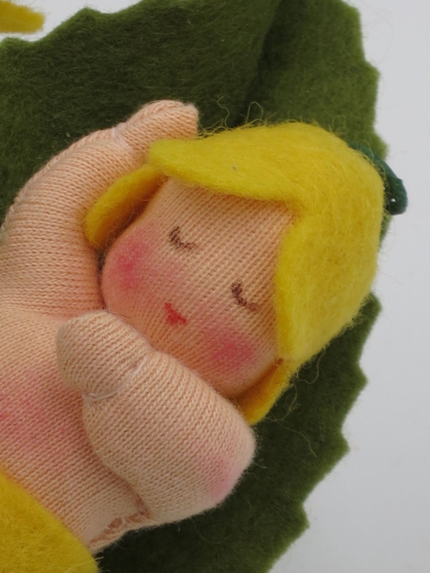 Nahaufnahme des schlafenden Schlüsselblumen-Baby-Gesichts im grünen Blatt