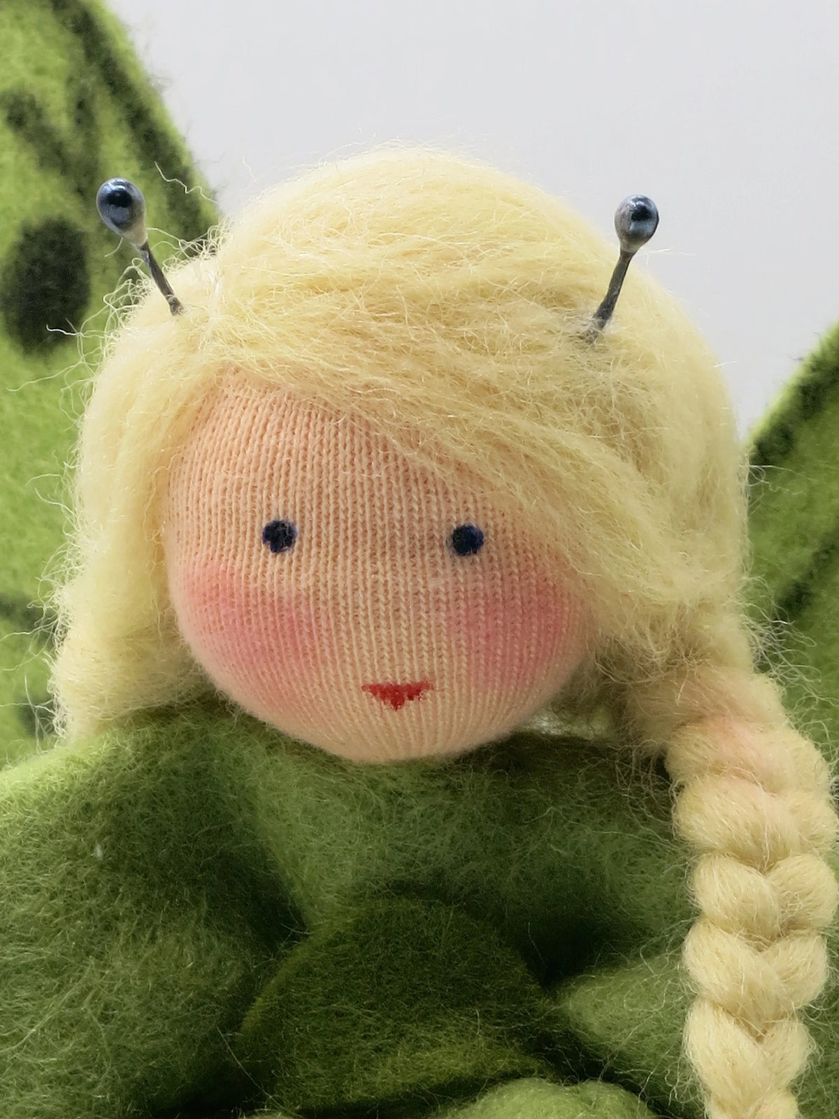 Nahaufnahme des Schmetterling-Blumenkind-Gesichts mit Draht-Fühlern und blondem Zopf