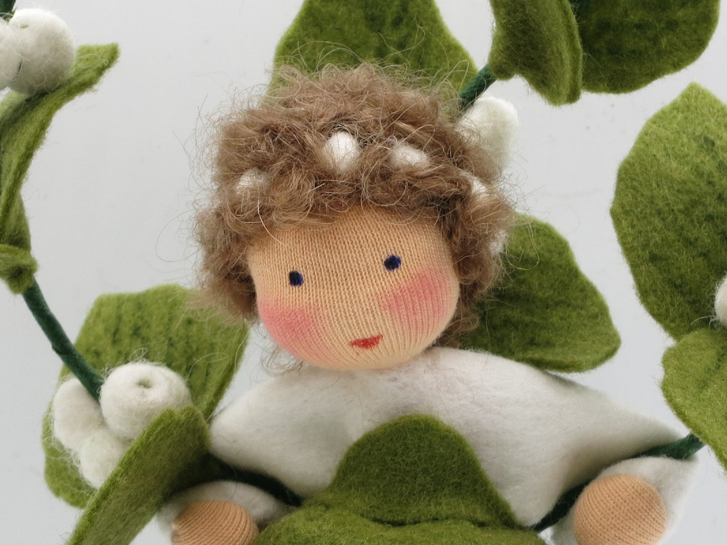Porträt der Schneebeere Art. HE57 mit weißem Oberteil und grünem Beerenzweig, Waldorf-Jahreszeitentisch.