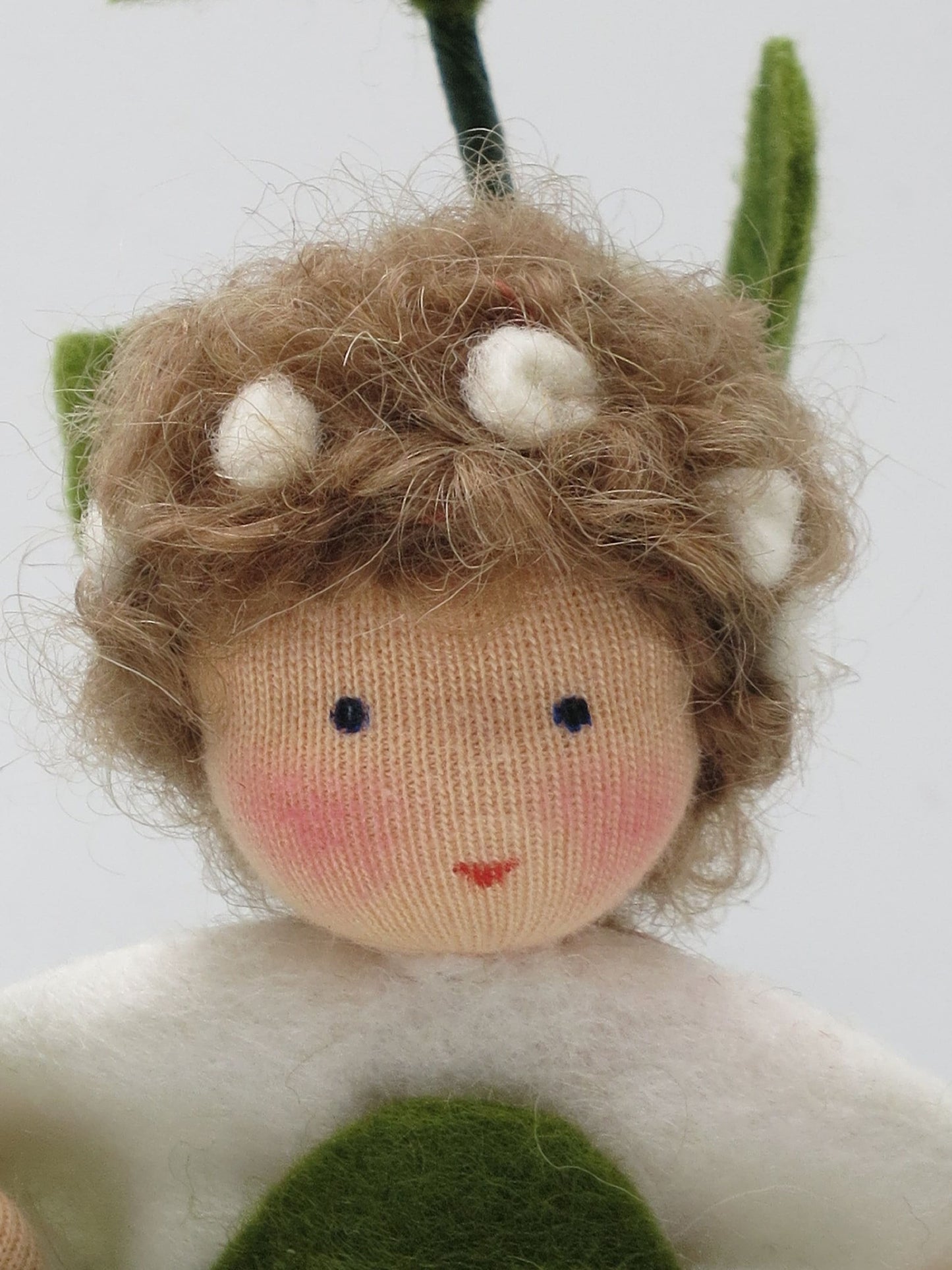 Nahaufnahme des Gesichts der Schneebeere Art. HE57 mit lockigem Haar und weißen Filzbeeren im Haar.