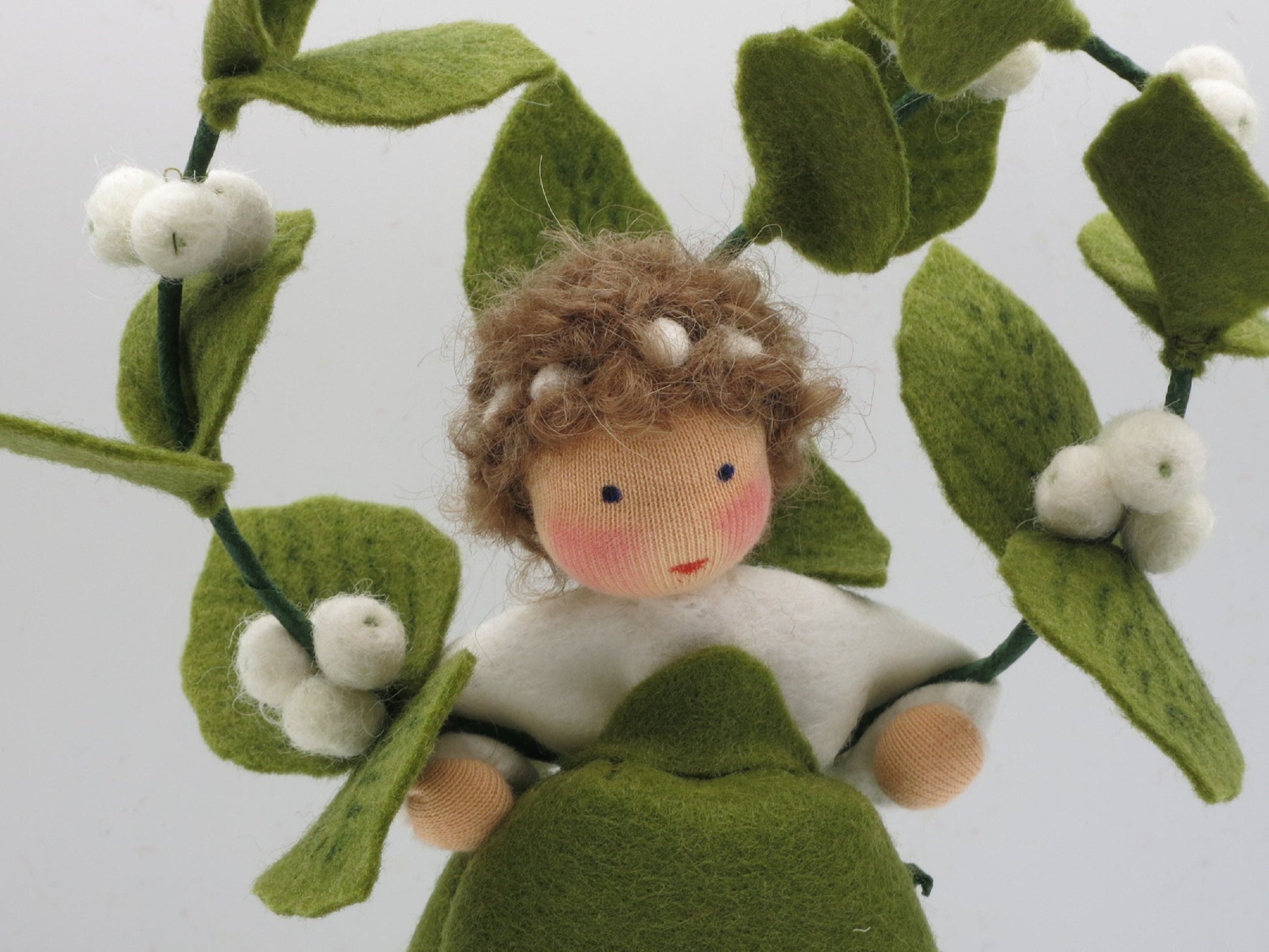 Nahaufnahme des Gesichts der Schneebeere Art. HE57 zwischen grünen Filzblättern und weißen Beeren.