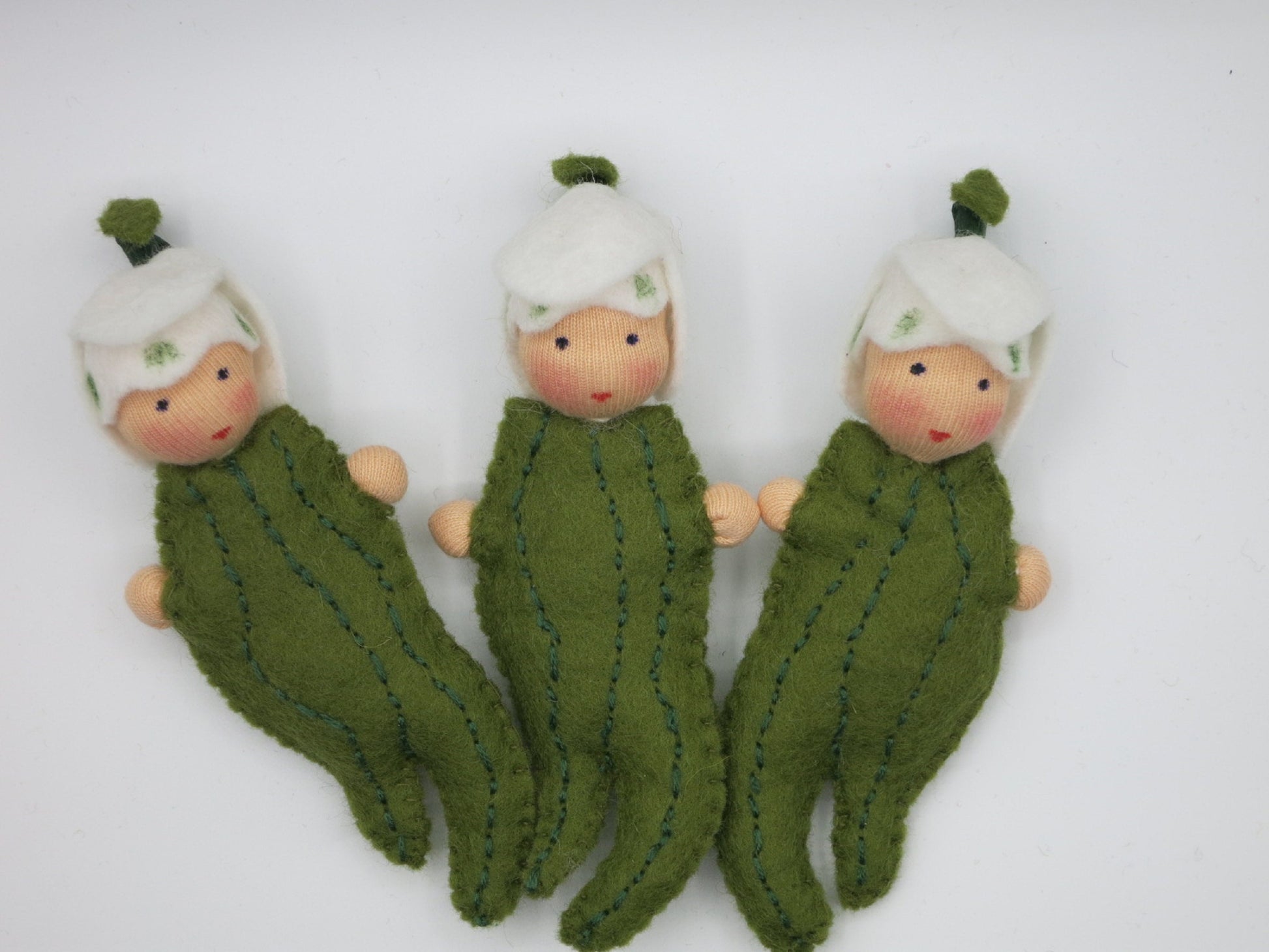 Drei handgefertigte Schneeglöckchen-Blätterkinder mit weißen Blütenhauben und grünen Filzblättern für den Jahreszeitentisch.