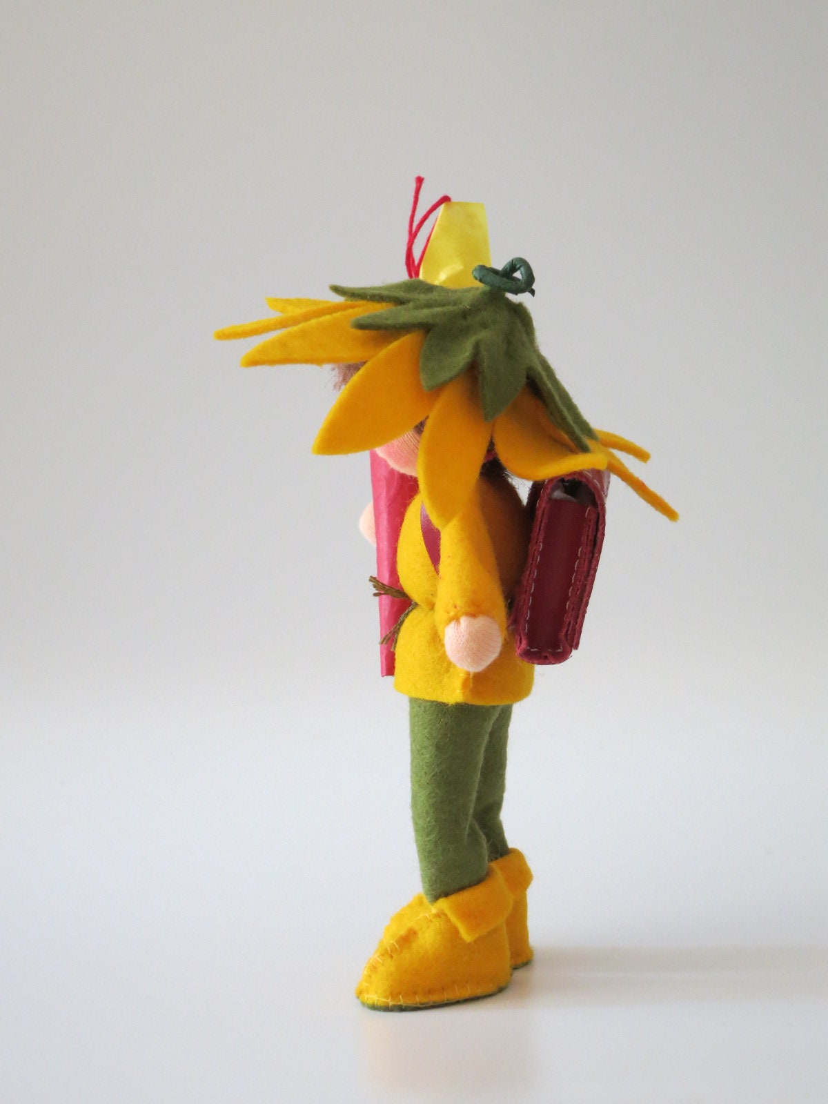 Seitenansicht des Schuljungen mit Sonnenblumen-Kapuze, Schulranzen und Schultüte