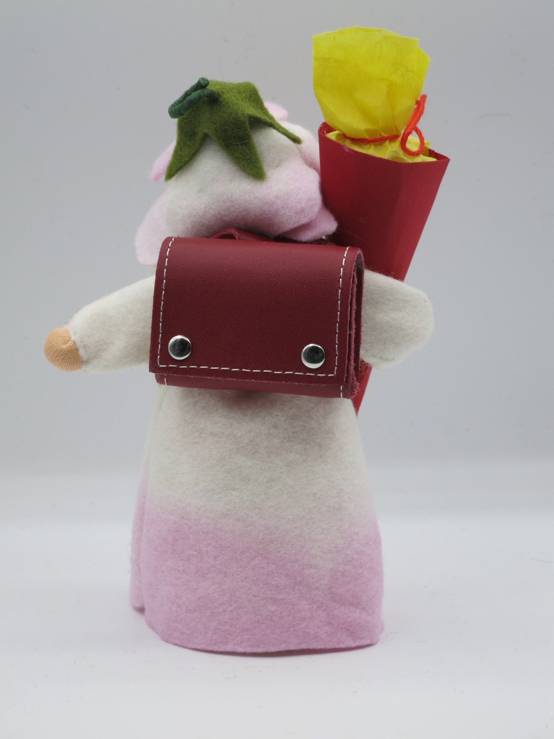 Rückansicht des Schulmädchen-Blumenkinds mit rotem Schulranzen und Schultüte mit gelbem Füllpapier.