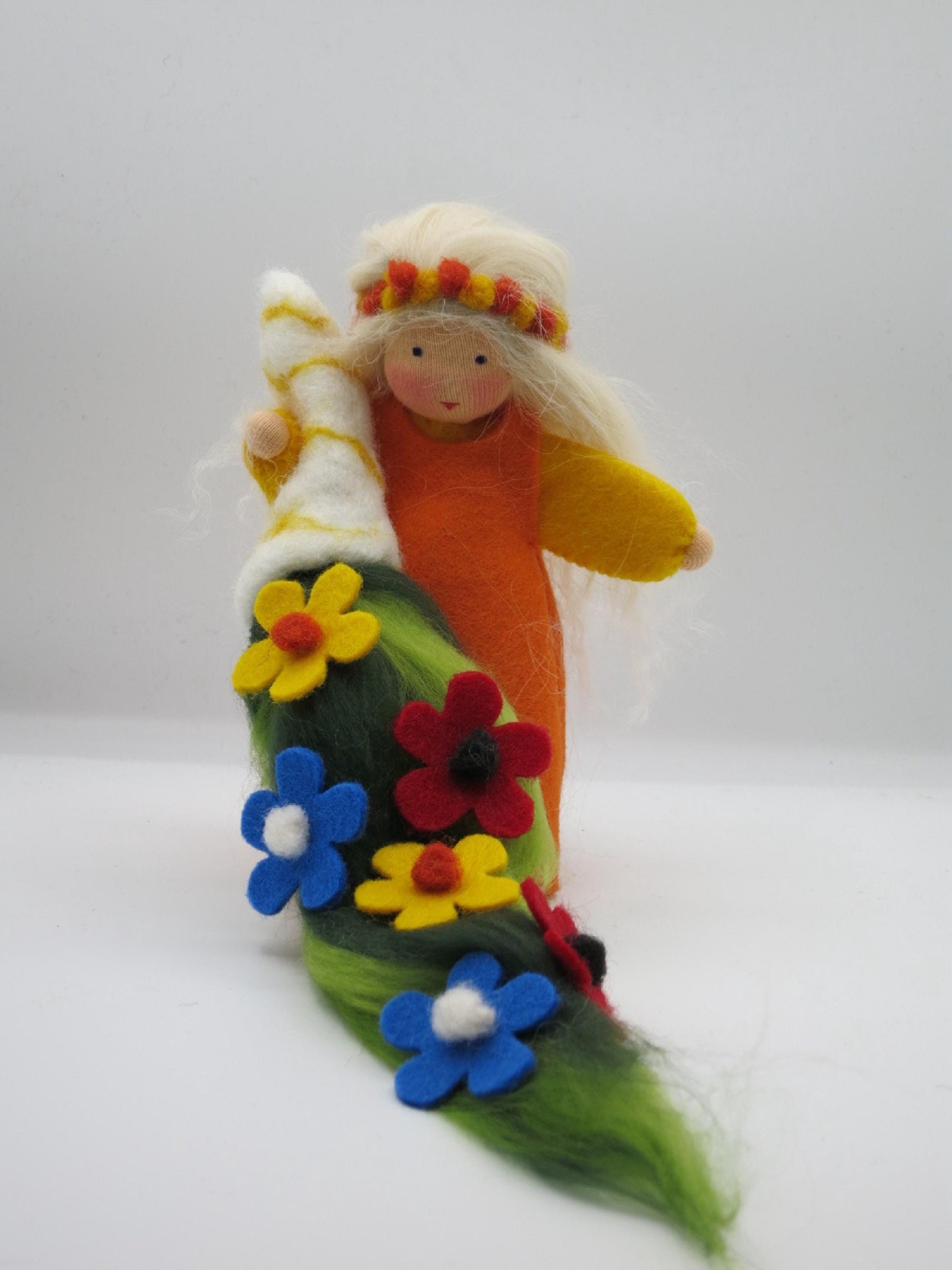Handgefertigte Sommerfigur in Orange und Gelb mit grünem Filzteppich und bunten roten, gelben und blauen Blumen