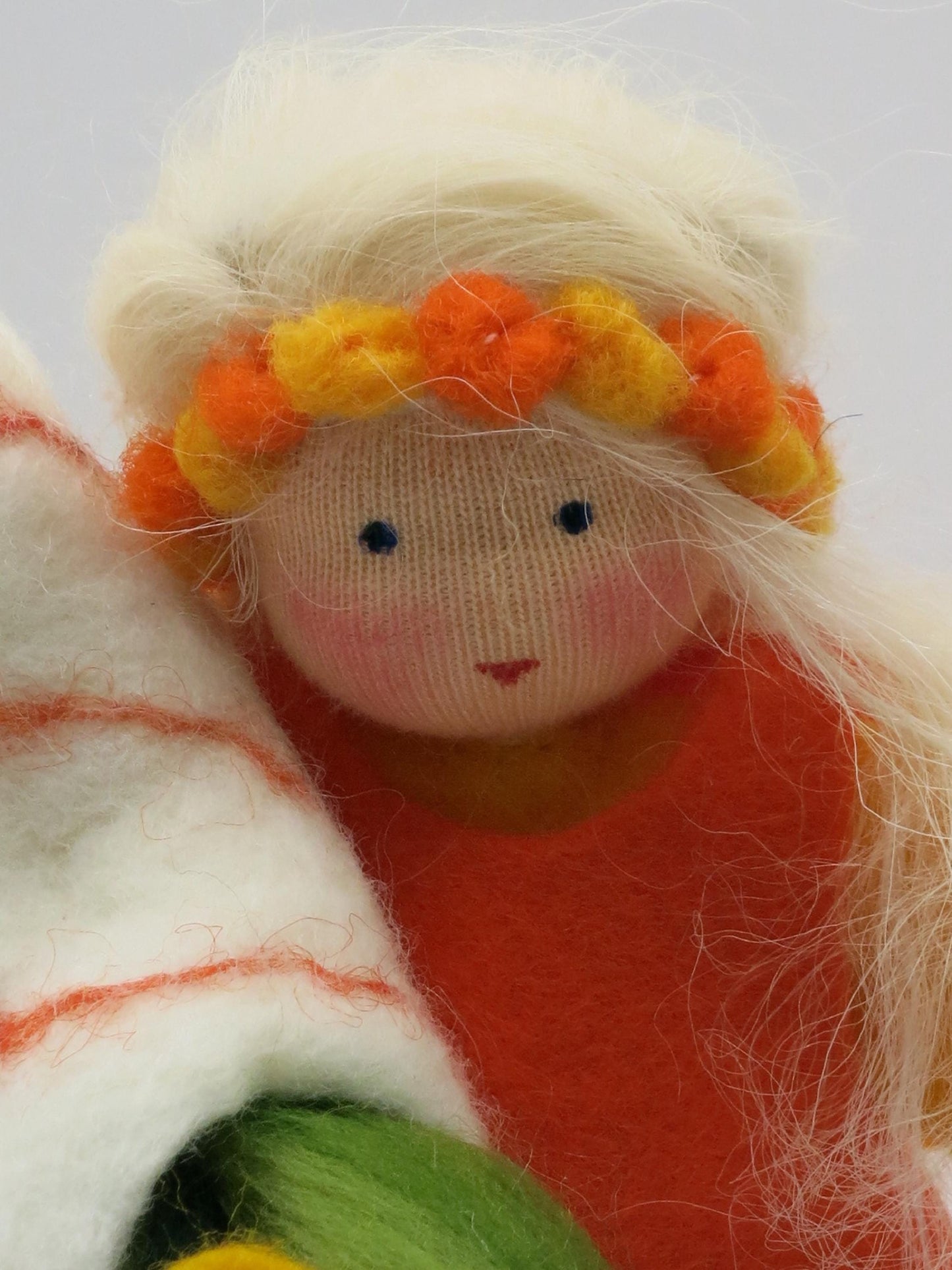 Detailporträt der Sommerfigur mit handgesticktem Gesicht, blondem Haar und orange-gelbem Filzblumenkranz