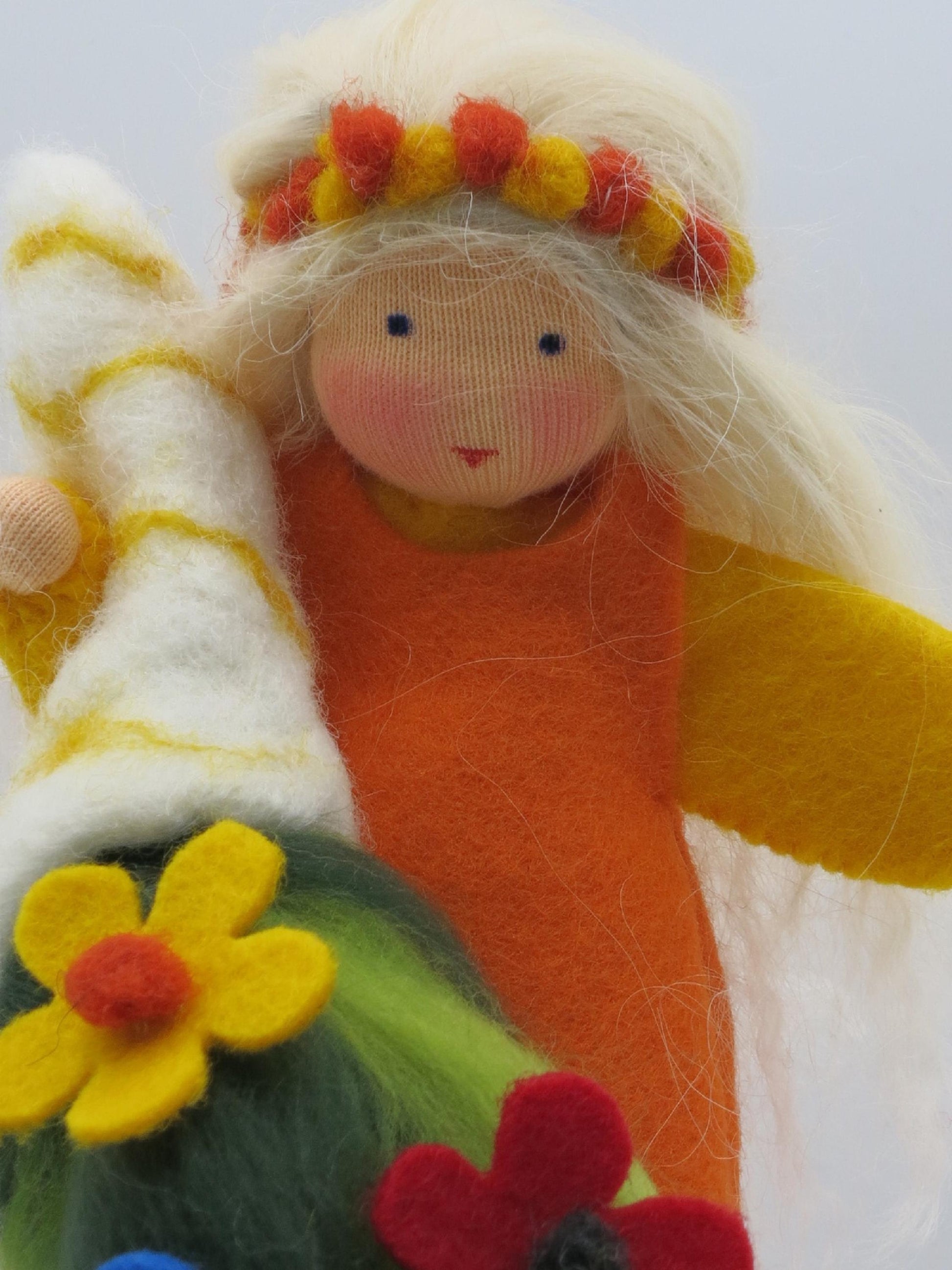 Porträt der Sommerfigur mit blondem Wollhaar, rot-gelbem Blumenkranz und orange-gelbem Filzgewand