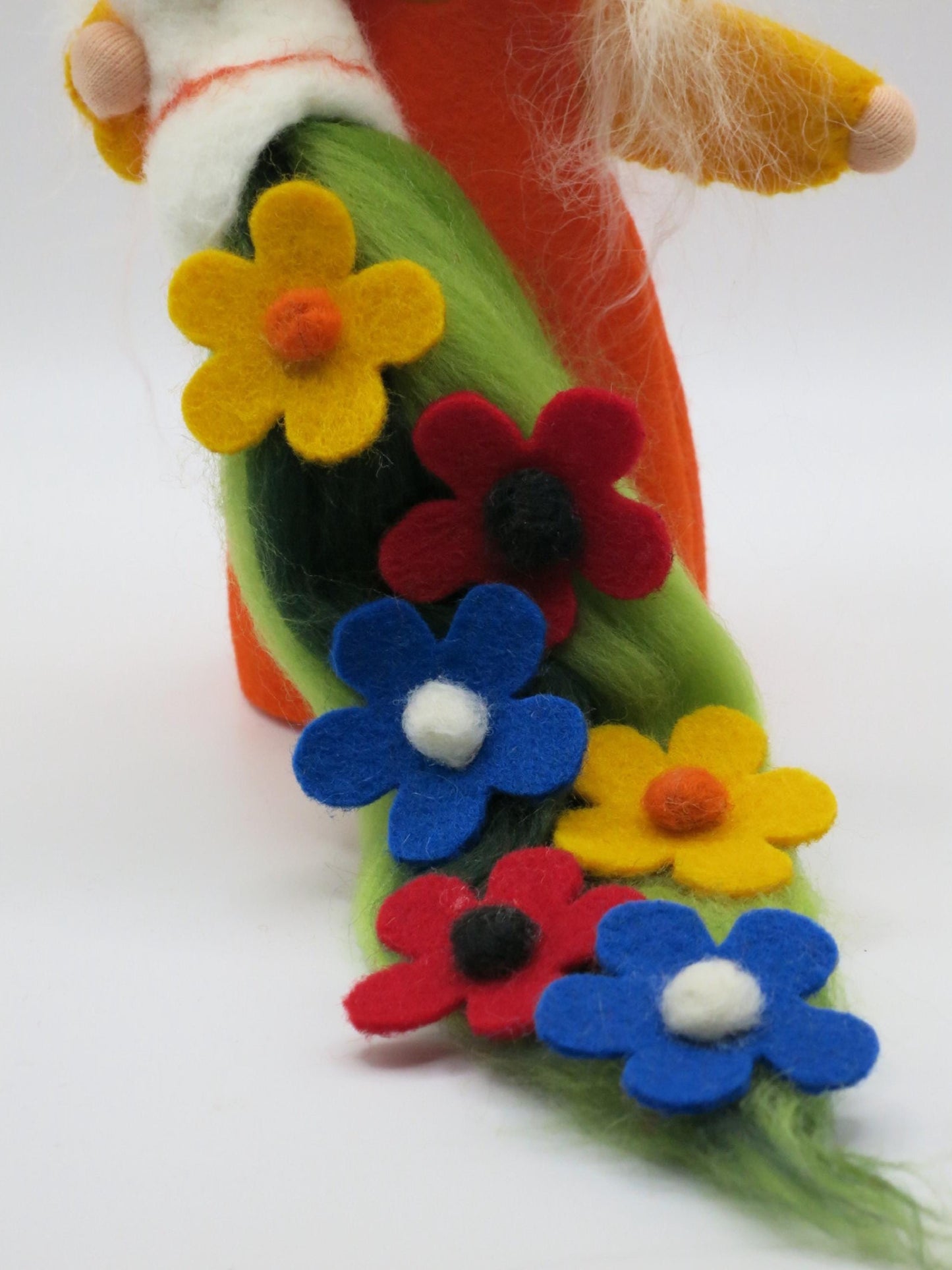 Detail des grünen Blumenteppichs mit handgearbeiteten gelben, roten und blauen Filzblüten