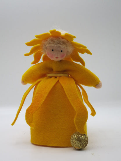Sonnen-Mädchen-Blumenkind aus Wollfilz mit strahlenförmigem gelb-orangem Kopfschmuck und glitzernder goldener Sonnenkugel zu Füßen, Waldorf-Figur für den Sommer-Jahreszeitentisch.