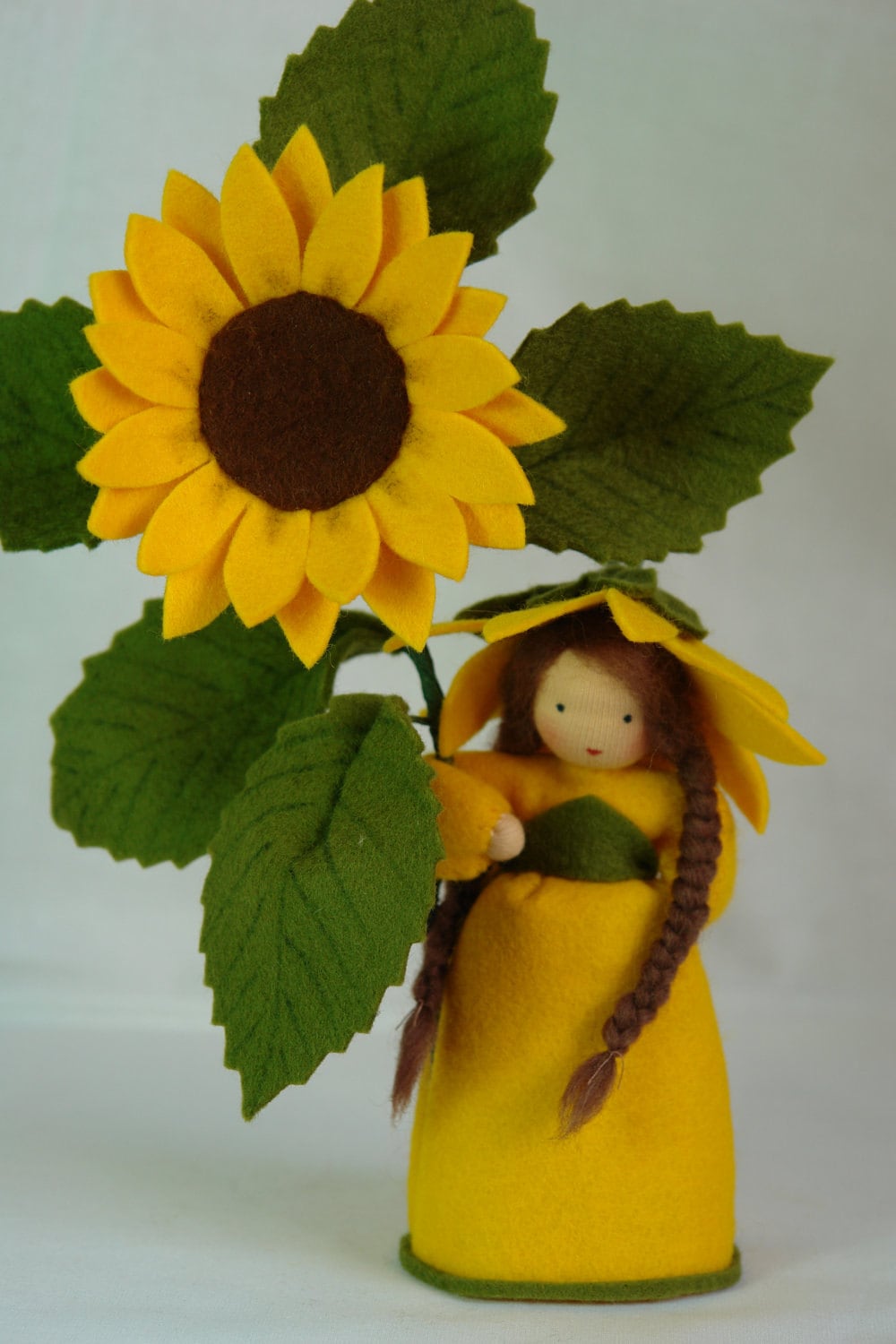 Sonnenblume-Figur mit brauner Blütenmitte und gezackten grünen Blättern am Stiel.
