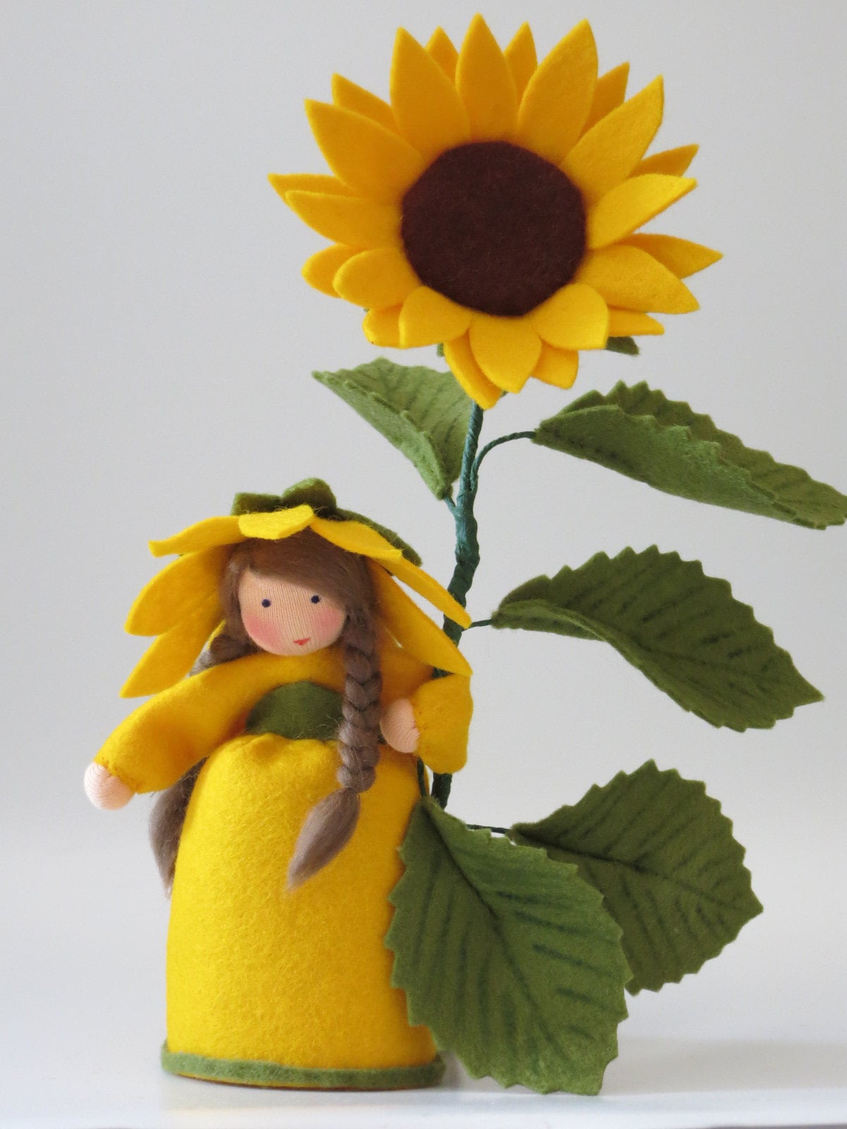 Sonnenblume-Blumenkind aus Wollfilz für den Waldorf Jahreszeitentisch, Variante mit dunkelbraunem Blütenkorb und gelben Strahlenblüten.