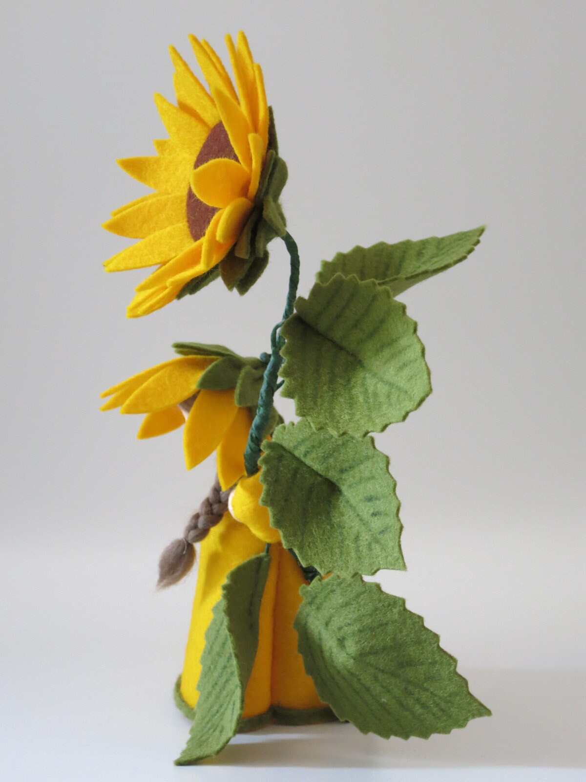Zwei Sonnenblumen-Blumenkinder im Vergleich, hintere Figur mit brauner Blütenmitte, vordere mit hellerer, gefüllter Blüte.