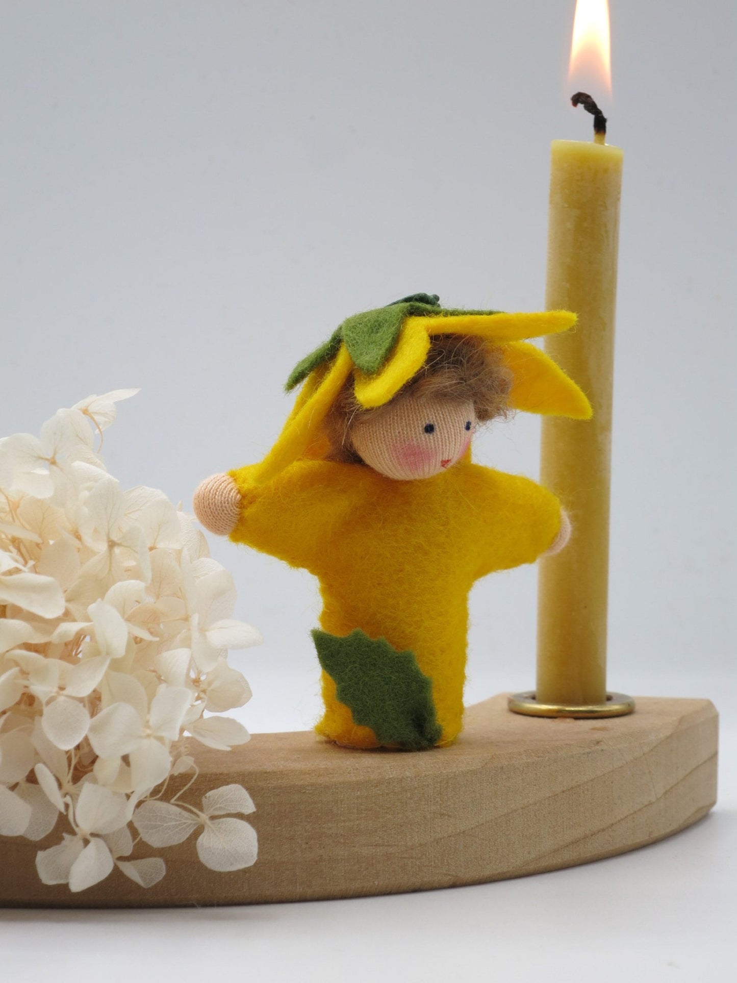 Sonnenblumenfigur aus Wollfilz mit Blütenblattkapuze neben Kerze, Waldorf-Geburtstagsring