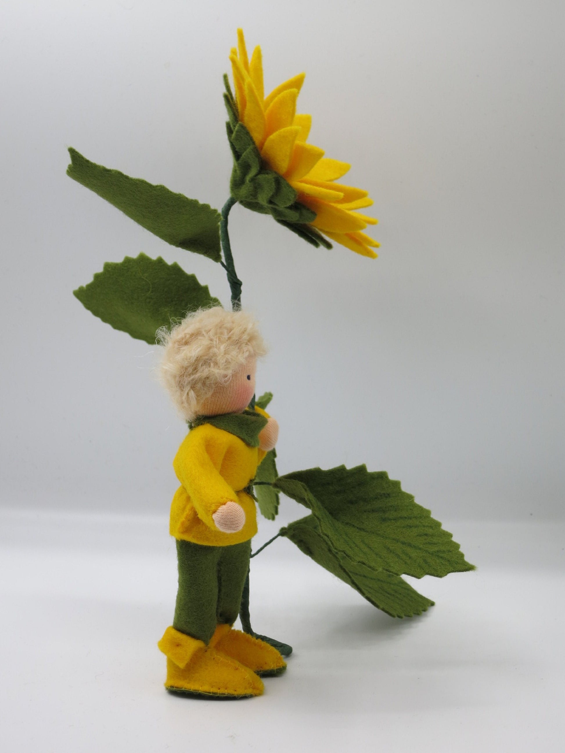 Seitenansicht des Sonnenblumen-Jungen mit gelbem Oberteil und großer Sonnenblume.