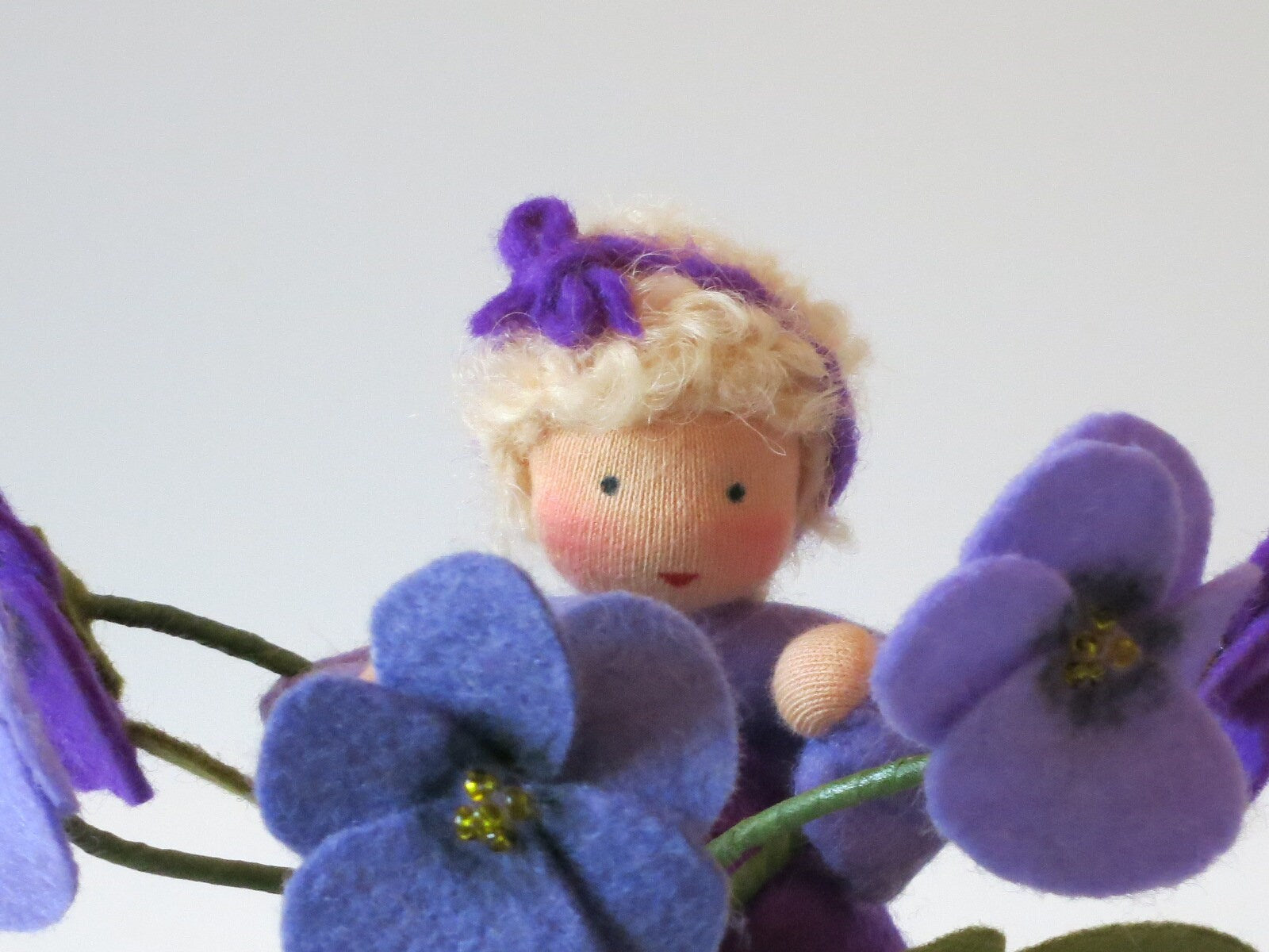 Nahaufnahme des Gesichts vom Stiefmütterchen-Blumenkind mit Blütenband im Haar