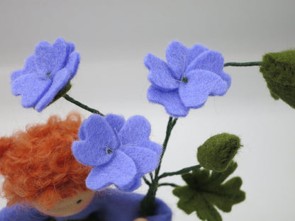 Nahaufnahme des Gesichts unter den violetten Blüten des Storchschnabel-Blumenkindes.