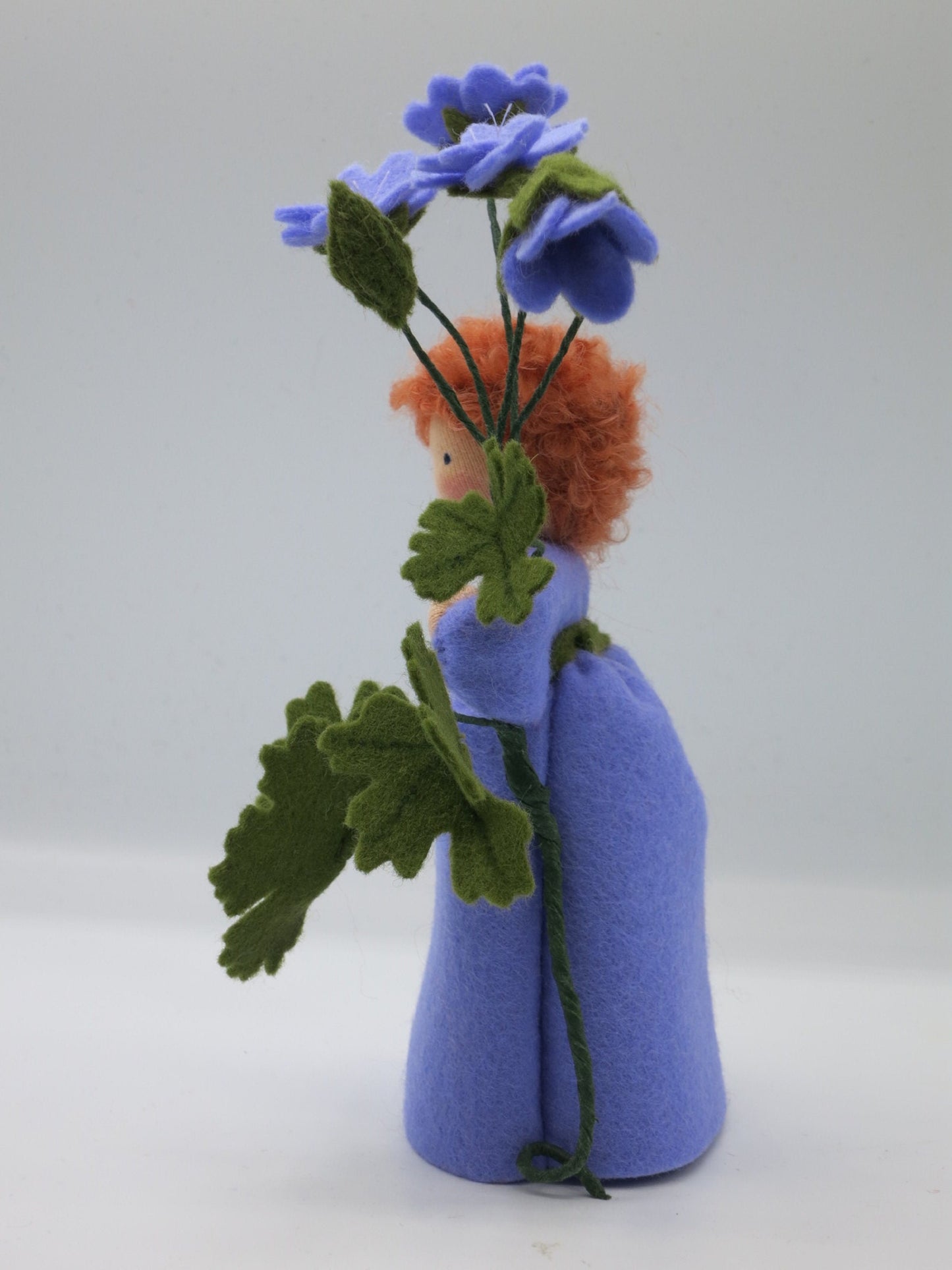 Porträt des Storchschnabel-Blumenkindes mit rotem Lockenhaar und violettem Filzkleid.