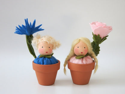 Rosen- und Kornblumen-Blumenkind mit rosa und blauer Filzblüte in zwei kleinen Terrakottatöpfen.