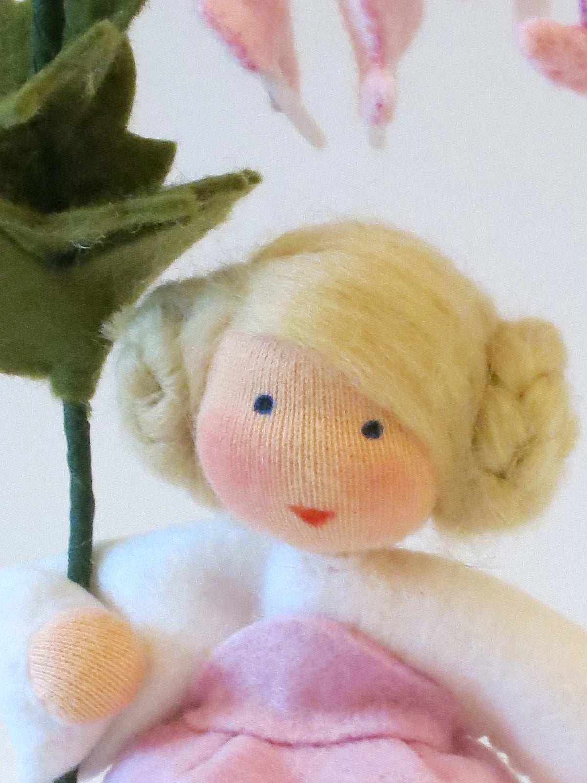 Nahaufnahme des Tränendes-Herz-Blumenkind-Gesichts mit blondem Haar unter den rosa Herzblüten