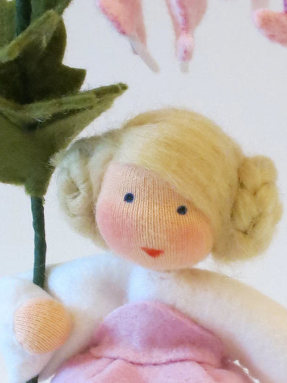 Nahaufnahme des Tränendes-Herz-Blumenkind-Gesichts mit blondem Haar unter den rosa Herzblüten