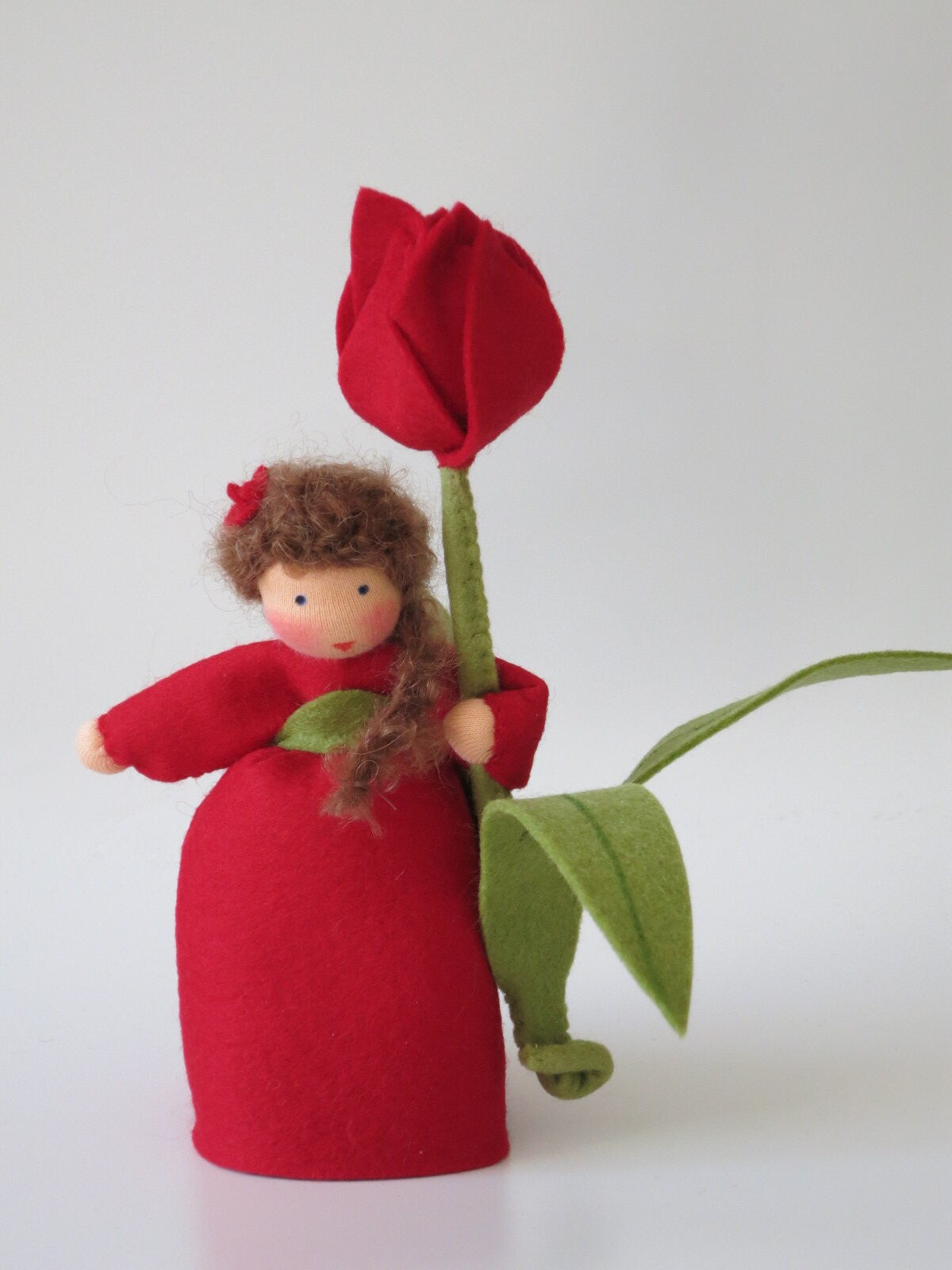 Rotes Tulpen-Blumenkind mit lockigem braunem Haar und großer roter Filztulpe
