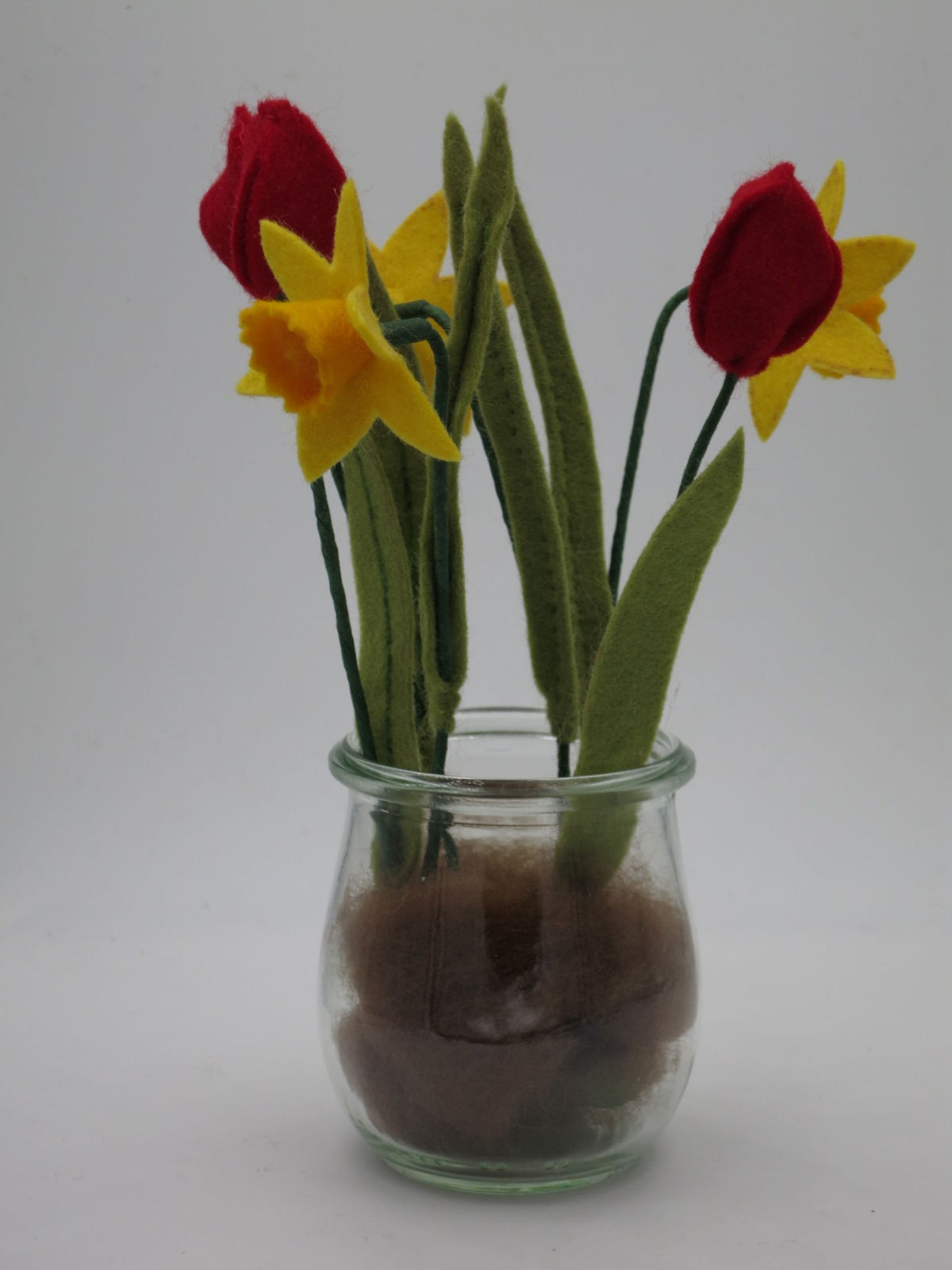 Filz-Tulpen und Osterglocken im Glas mit brauner Wollfilz-Erde als Ostertischdeko