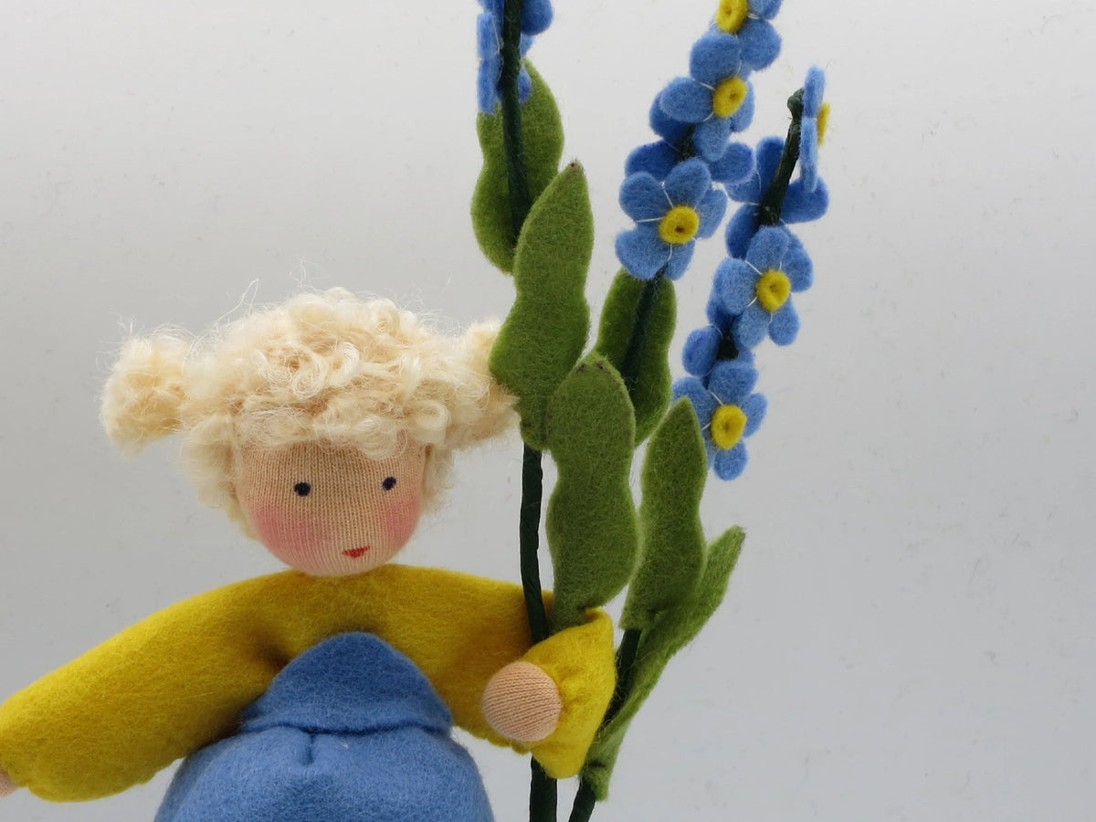 Nahaufnahme des Vergissmeinnicht-Blumenkind-Gesichts mit blauen Blütentrauben im Hintergrund