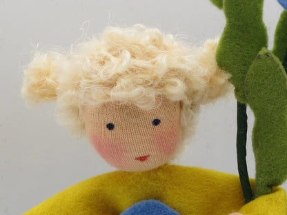 Porträt des Vergissmeinnicht-Blumenkinds mit blondem Lockenhaar und blauem Filzkleid