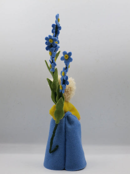 Rückansicht des Vergissmeinnicht-Blumenkinds mit blondem Haar und blauem Filzkleid