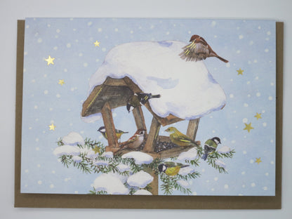 Weihnachtskarte mit schneebedecktem Futterhäuschen, Spatz im Landeanflug, Kohlmeise und Grünfink, Grätz Verlag, Art. PKWei94