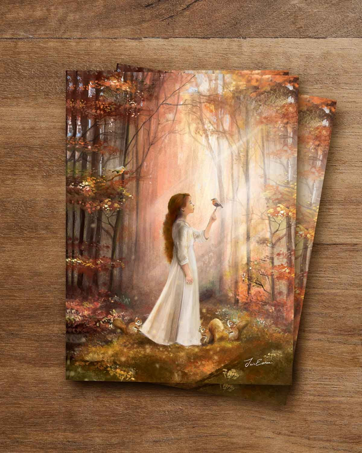 Herbstwald Bild auf der Postkarte „Waldgeflüster“ von Iris Esther: junge Frau mit langem rotbraunem Haar im weißen Kleid hält ein Rotkehlchen auf der erhobenen Hand, ein zweites sitzt im Baum, drei Eichhörnchen am Waldboden, Sonnenstrahlen zwischen rotem und goldenem Laub