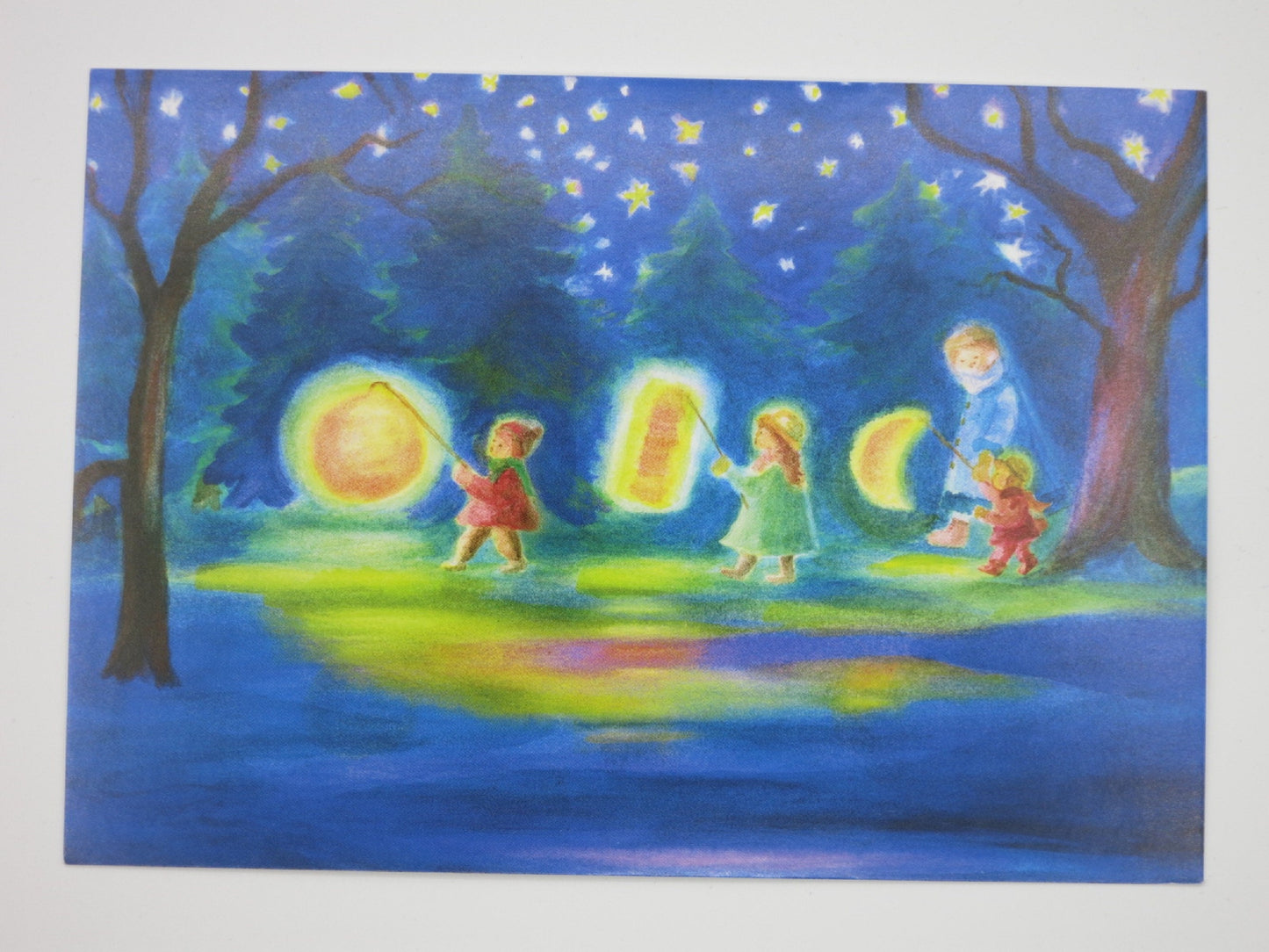 Kinder mit Sonnen-, Mond- und Sternlaterne spiegeln sich im Wasser – Waldorf Postkarte Laternenumzug von Dorothea Schmidt