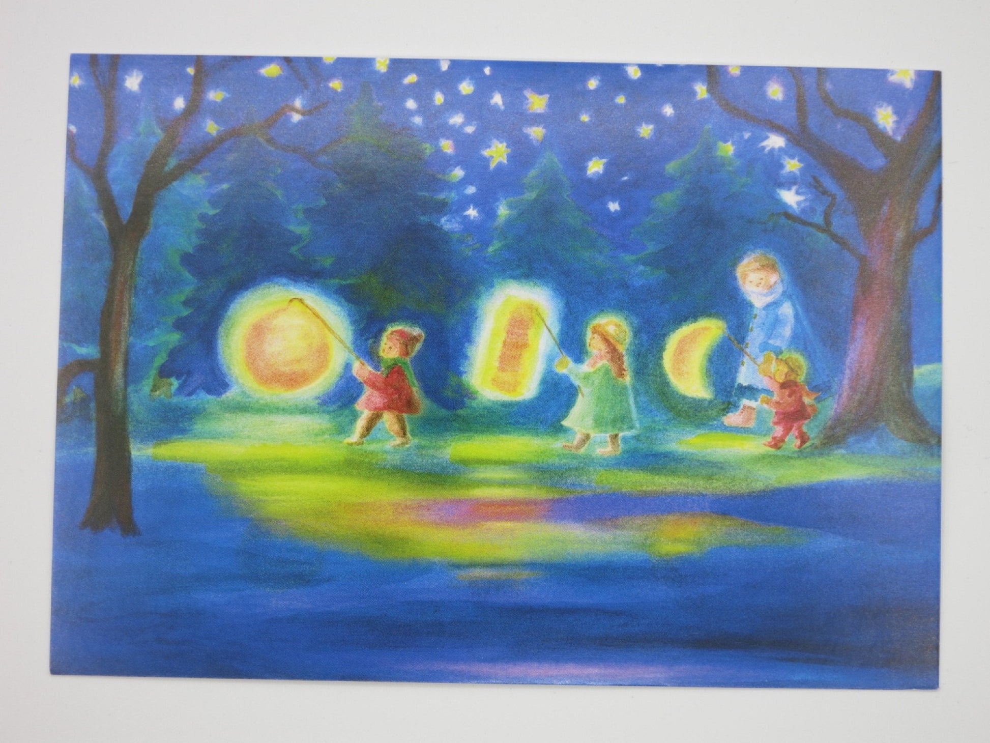 Kinder mit Sonnen-, Mond- und Sternlaterne spiegeln sich im Wasser – Waldorf Postkarte Laternenumzug von Dorothea Schmidt