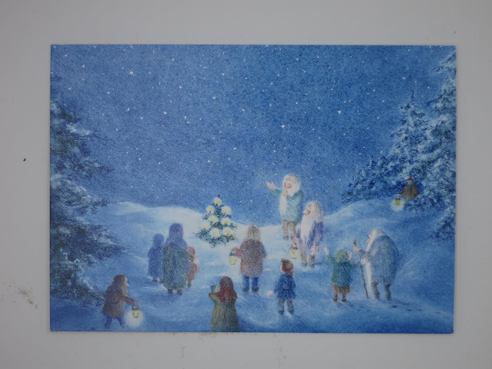 Postkarte Waldweihnacht von Monika Speck, Zwerge mit Laternen versammeln sich um kleines Tannenbaeumchen im Winterwald