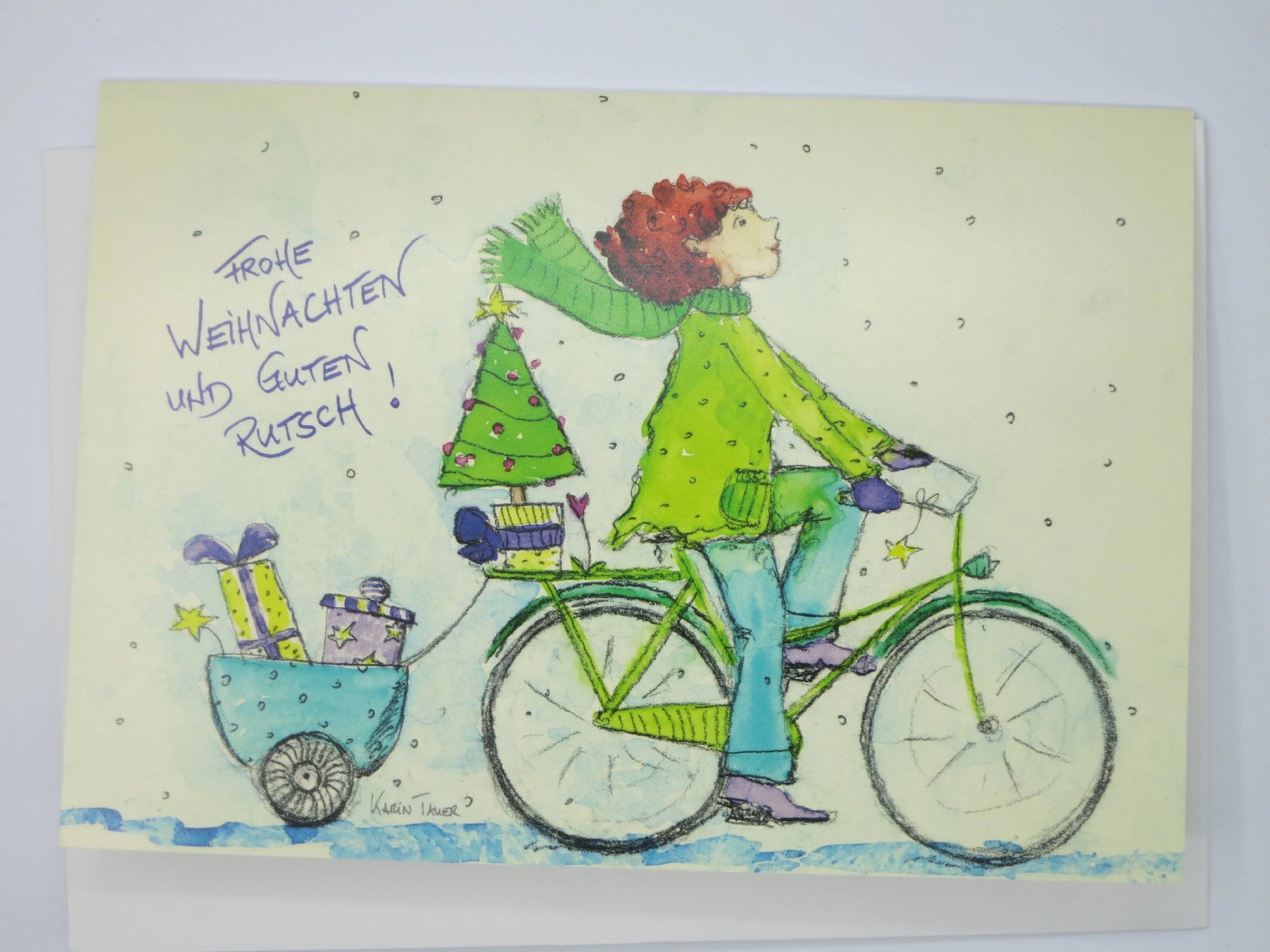 Weihnachtskarte mit Umschlag 'Frohe Weihnachten und einen guten Rutsch' von Karin Tauer: Person auf dem Fahrrad transportiert Weihnachtsbaum und Geschenke im Anhänger.
