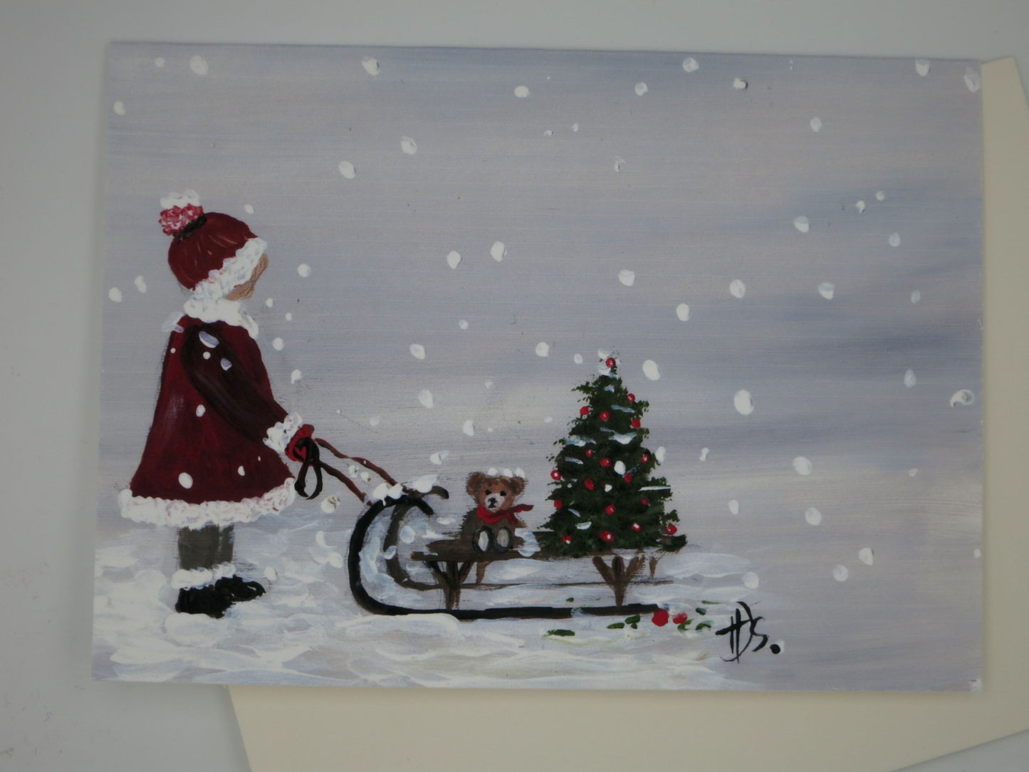 Weihnachtskarte Mädchen zieht Schlitten mit Teddybär und Mini-Tannenbaum durch den Schnee