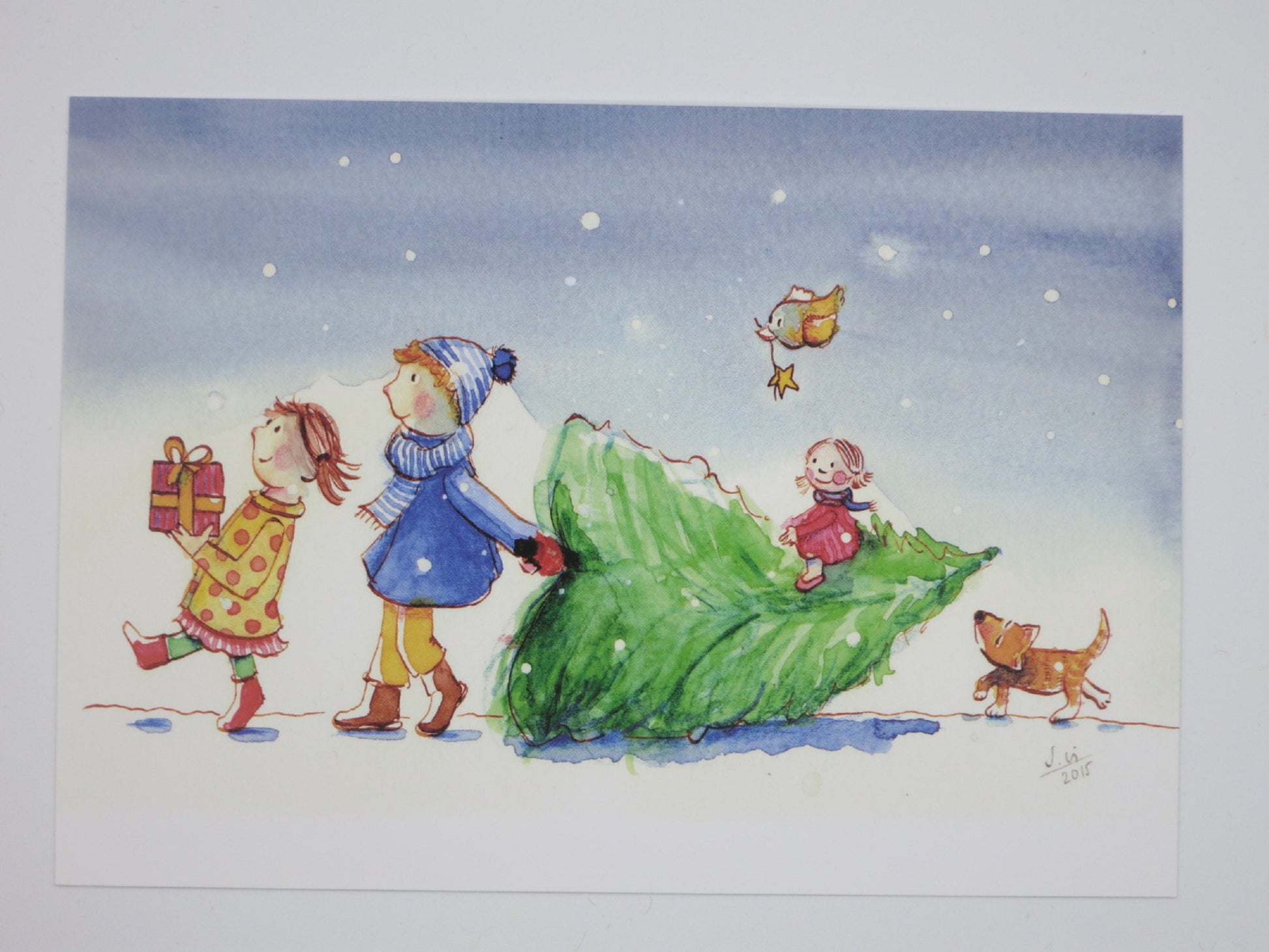 Weihnachtspostkarte für Kinder: zwei Kinder ziehen einen Tannenbaum durch den Schnee, Rotkehlchen mit Stern, Waldorf Jahreszeitentisch Winter