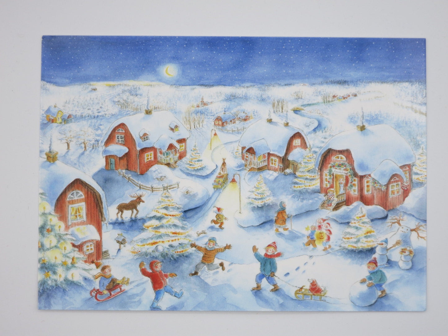 Kunstpostkarte Weihnachtszeit von Dorle Schausbreitner – verschneites Dorf mit spielenden Kindern, PKWI79
