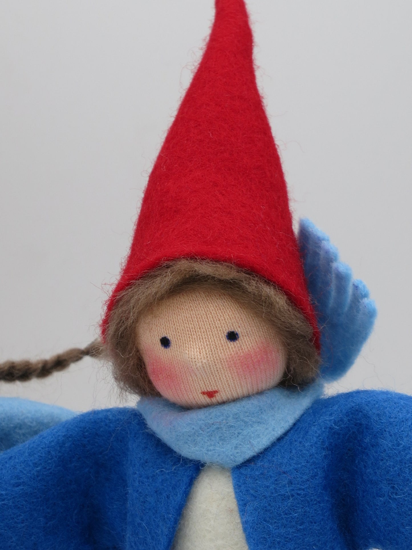 Nahaufnahme des Gesichts vom Wichteljungen Art. WI63 mit rotem Zipfelmützchen, Waldorf-Jahreszeitentisch.