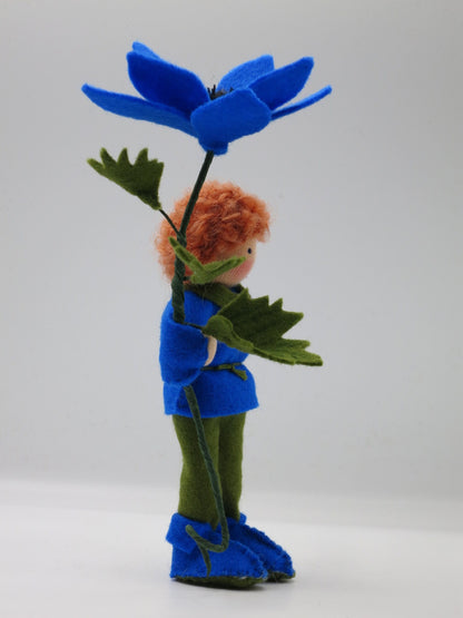 Seitenansicht des blauen Windröschen-Blumenkinds als Junge mit großer Filzblüte und grünen Blättern.